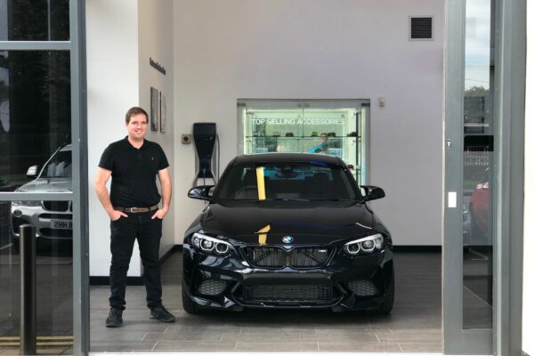 Vincent Noott standing next to a black BMW, vince is the founder of source my car, UK wide car sourcing